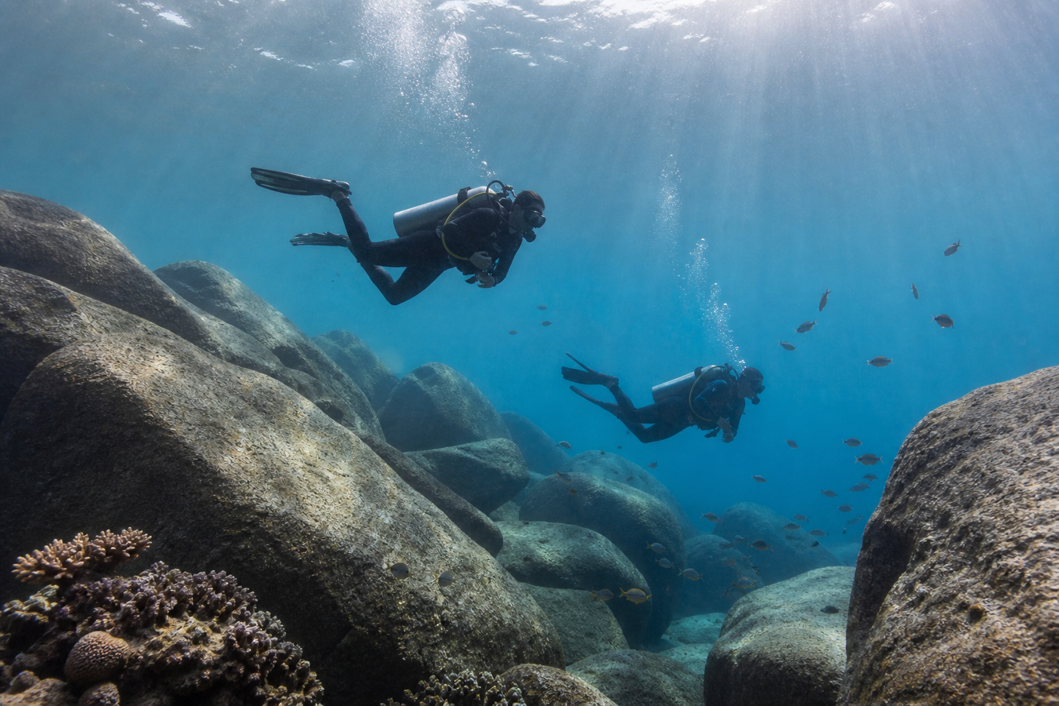 Deux plongeurs évoluant entre des blocs de granit dans les eaux claires des Seychelles
